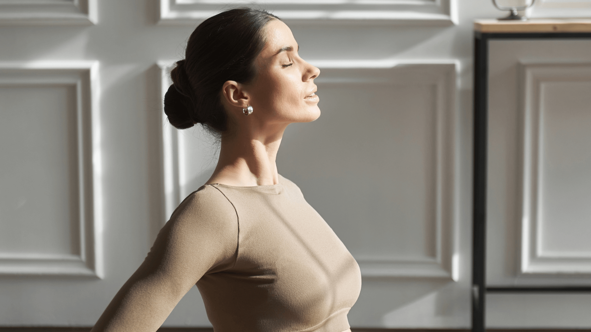 A peaceful woman sitting with her eyes closed in a sunlit room, symbolizing the improved mood, energy, and overall well-being achieved through bioidentical hormone pellet therapy.
