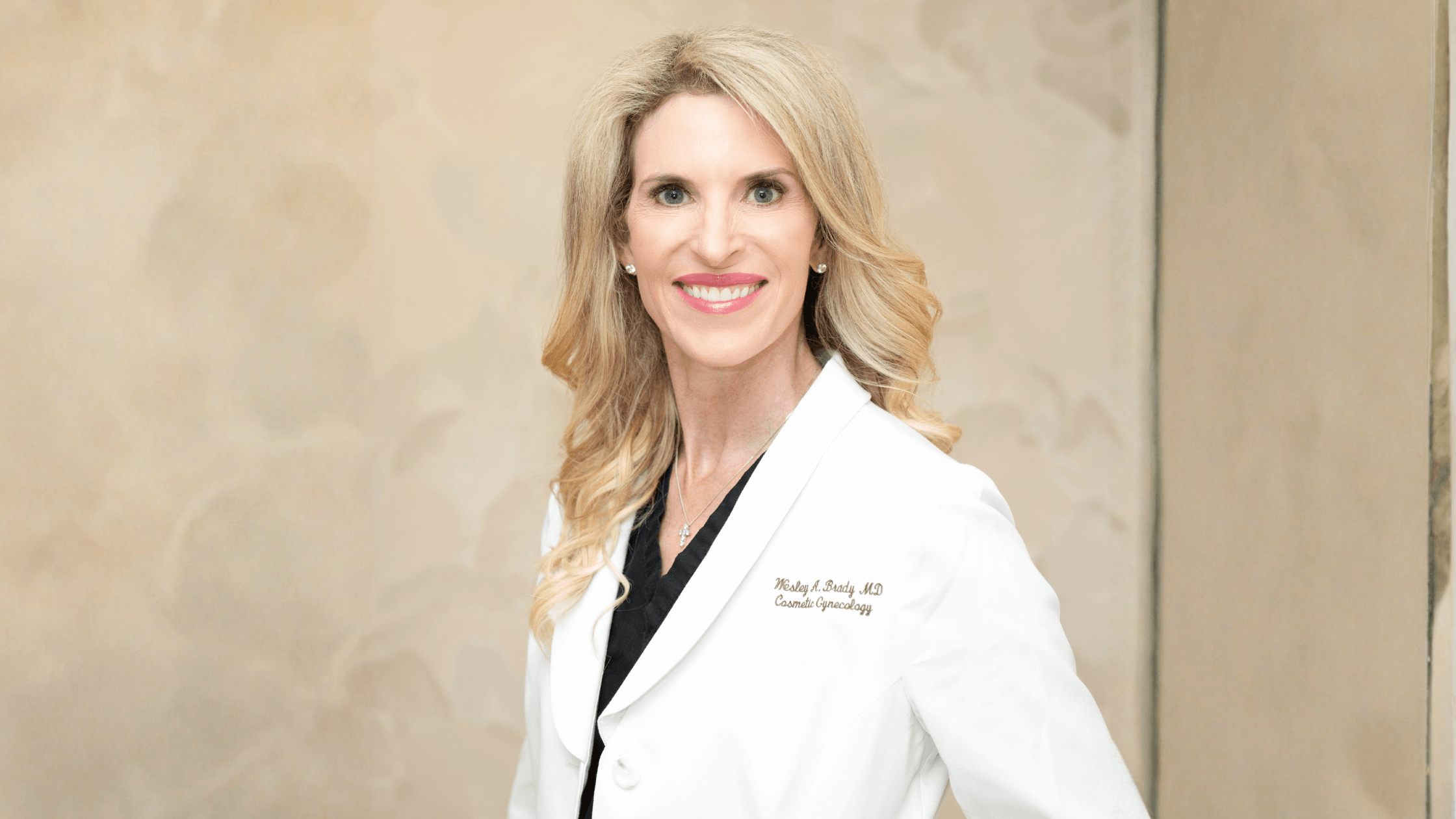 Dr. Wesley Anne Brady, a board-certified gynecologic surgeon and the first female cosmetic gynecologist in Dallas, wearing a white clinical coat.